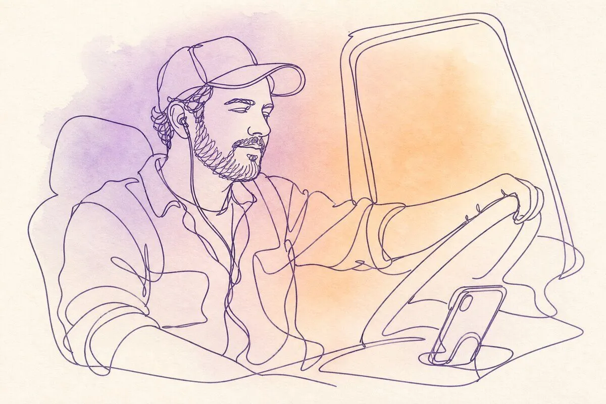 A man in a truck cab with a phone on the dashboard, listening